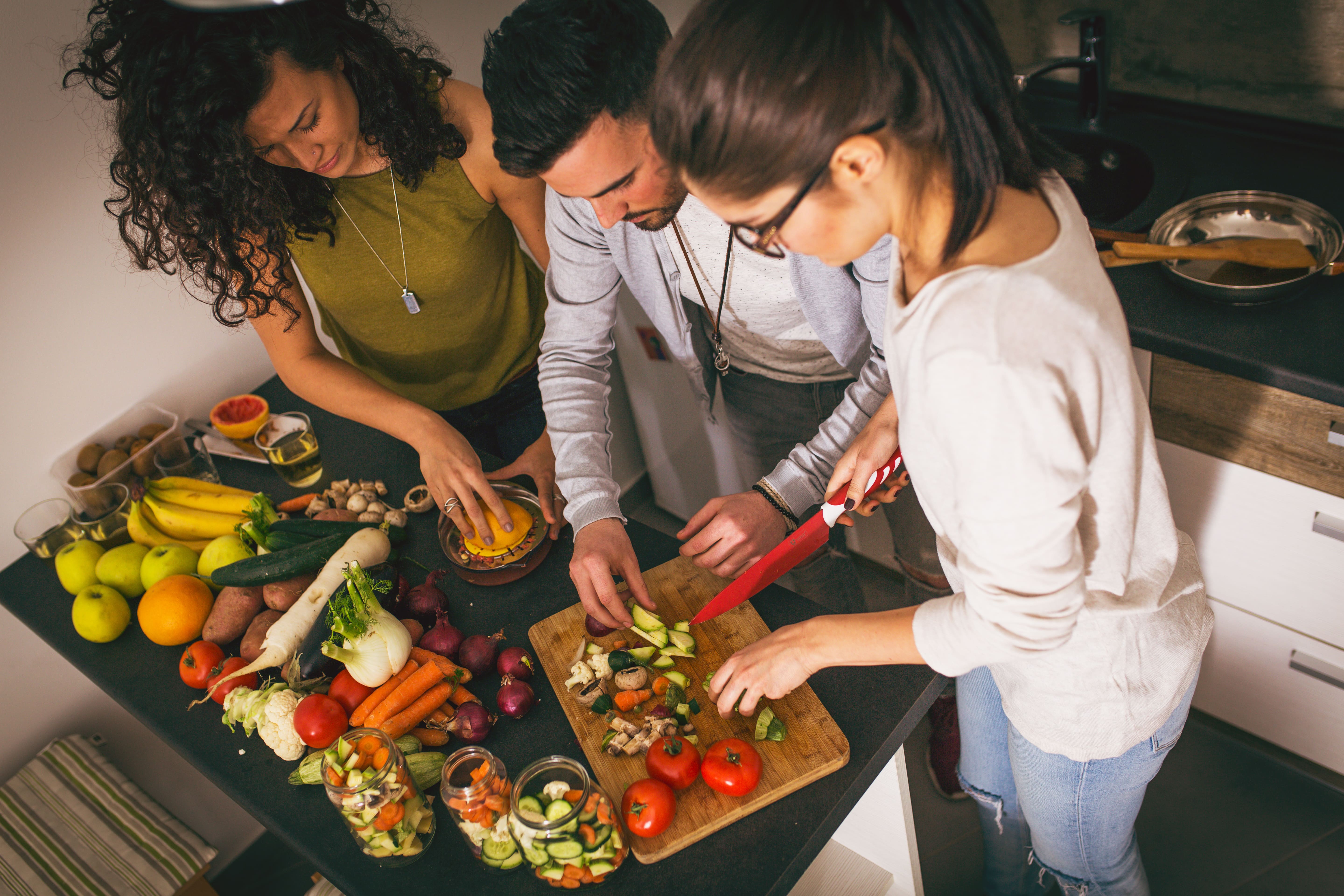  Three people are preparing food in a kitchen.