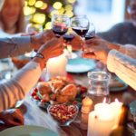 A group of people clinking their wine glasses over a table of food